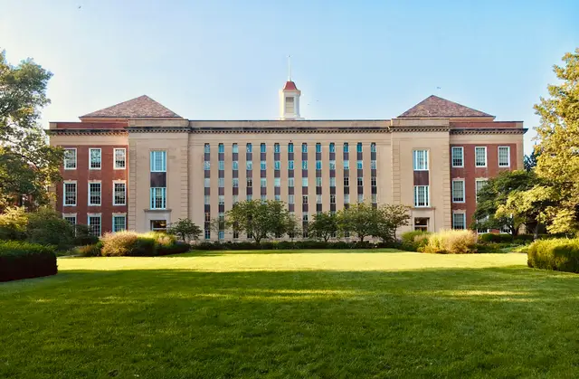 Sunlit campus buildings facing a green lawn